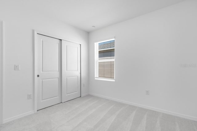 unfurnished bedroom featuring a closet, baseboards, and light carpet