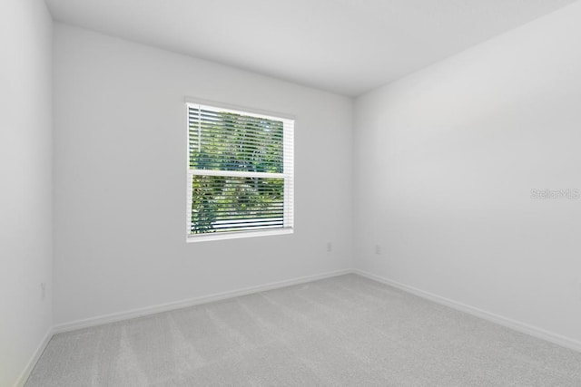 spare room featuring baseboards and light colored carpet
