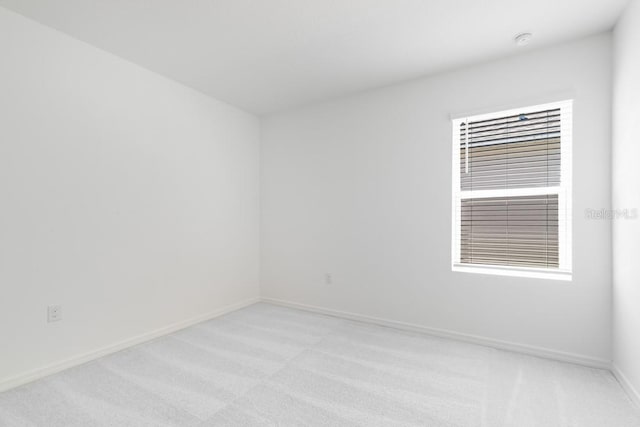 spare room with baseboards and light carpet