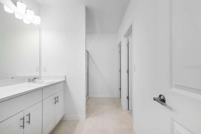 bathroom with baseboards, vanity, and a shower with door