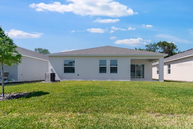 back of house with a lawn, central AC, and stucco siding