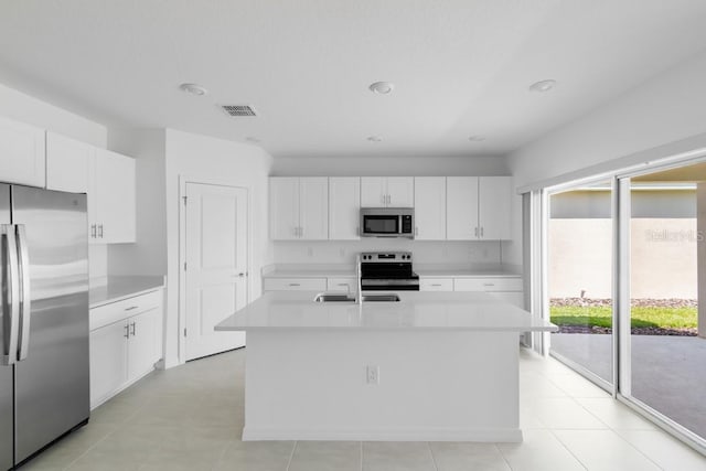 kitchen with a sink, a kitchen island with sink, stainless steel appliances, light countertops, and visible vents