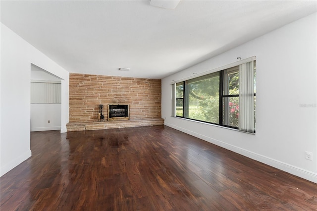 unfurnished living room featuring a stone fireplace, wood finished floors, and baseboards