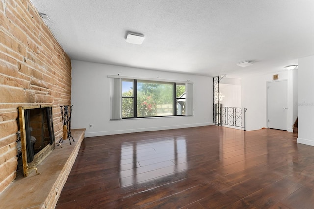 unfurnished living room with baseboards, a textured ceiling, a stone fireplace, and hardwood / wood-style floors