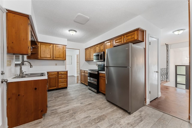 kitchen featuring a sink, light countertops, brown cabinetry, stainless steel appliances, and open shelves