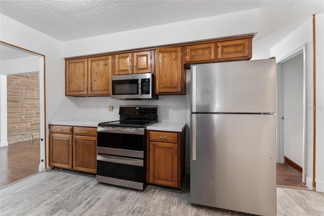 kitchen with appliances with stainless steel finishes, brown cabinetry, and light countertops