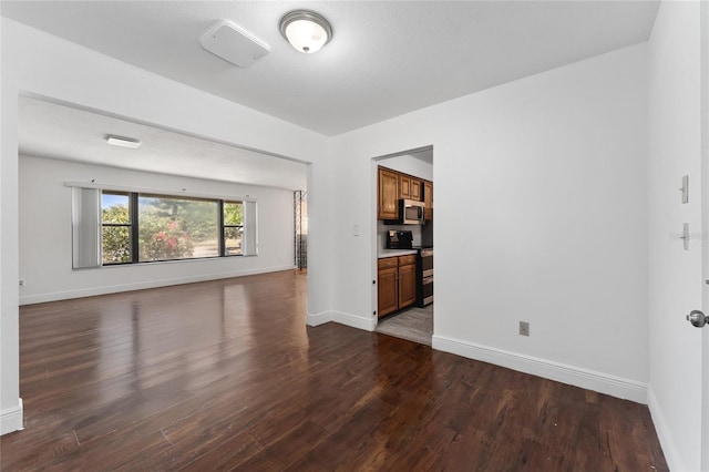 unfurnished living room featuring baseboards and dark wood finished floors