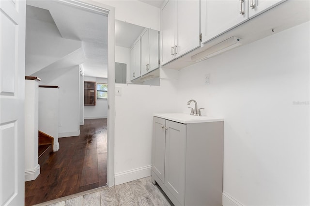 laundry room featuring light wood-style floors, baseboards, and a sink