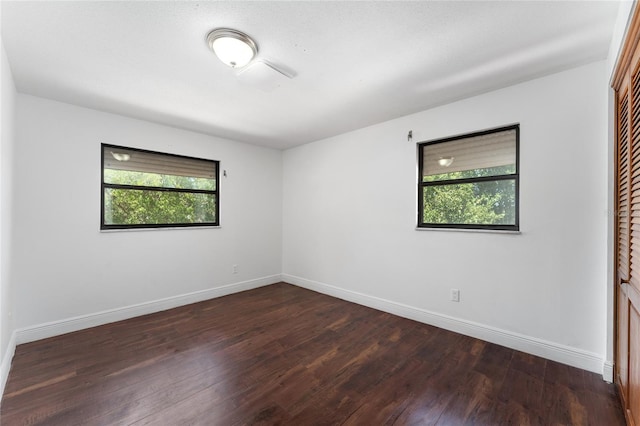 unfurnished room with dark wood-type flooring and baseboards