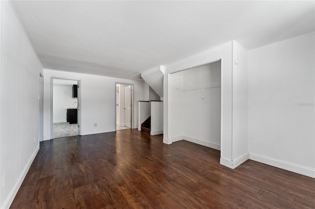 unfurnished living room featuring baseboards and hardwood / wood-style flooring