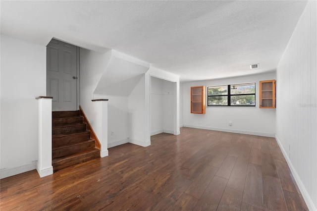 interior space featuring visible vents, a textured ceiling, stairway, wood-type flooring, and baseboards