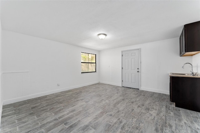 unfurnished living room with a sink, light wood-type flooring, and baseboards