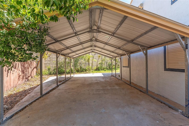 view of parking / parking lot featuring a detached carport and fence