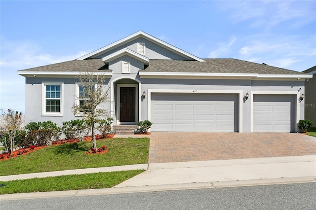 ranch-style house with roof with shingles, an attached garage, stucco siding, a front lawn, and decorative driveway