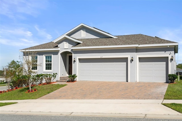 ranch-style house with a garage, decorative driveway, stucco siding, and a shingled roof