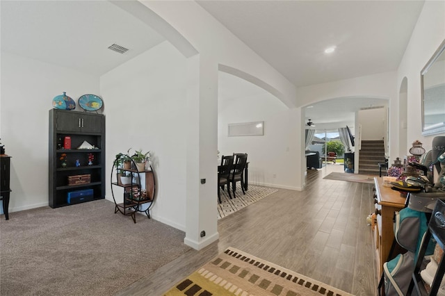 corridor featuring wood finished floors, stairway, visible vents, and arched walkways