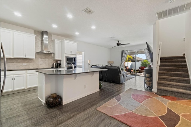 kitchen featuring visible vents, appliances with stainless steel finishes, open floor plan, and wall chimney range hood