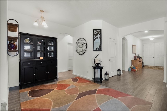 interior space featuring baseboards, light wood-type flooring, arched walkways, and an inviting chandelier