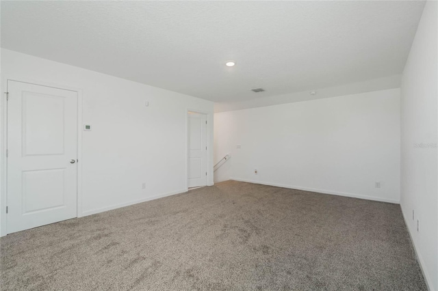 spare room with visible vents, baseboards, carpet, and a textured ceiling