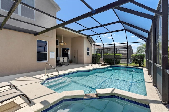 view of pool with glass enclosure, a patio, a ceiling fan, and a pool with connected hot tub