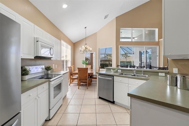 kitchen with dark countertops, vaulted ceiling, appliances with stainless steel finishes, and a sink