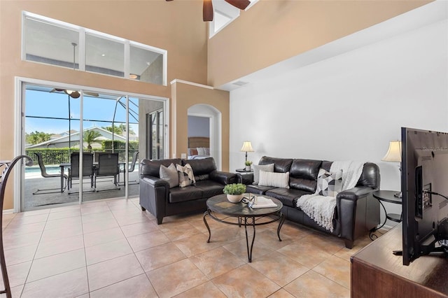 living area featuring visible vents, light tile patterned flooring, arched walkways, a sunroom, and ceiling fan