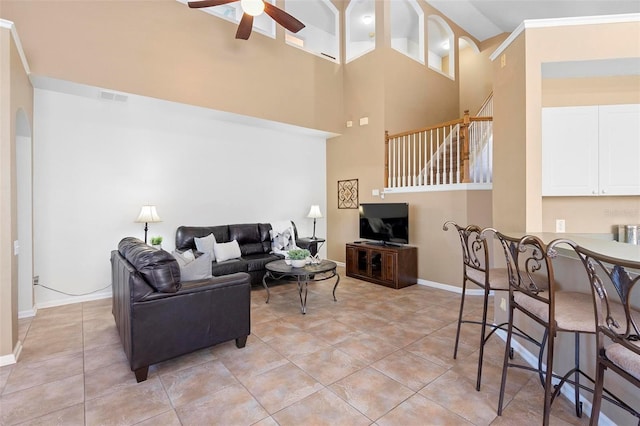 living room featuring baseboards, visible vents, light tile patterned flooring, ceiling fan, and a towering ceiling