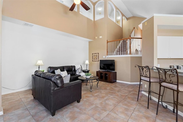 living area featuring a ceiling fan, visible vents, baseboards, a high ceiling, and light tile patterned flooring