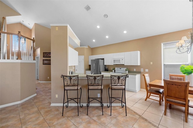 kitchen featuring white microwave, a peninsula, freestanding refrigerator, white cabinetry, and a notable chandelier