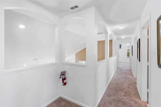 hall with visible vents, baseboards, and carpet