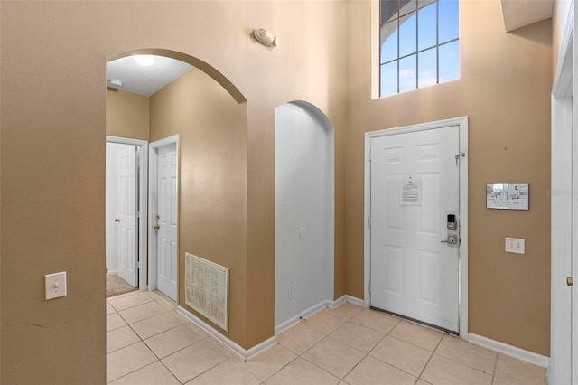 entryway featuring a high ceiling, light tile patterned flooring, arched walkways, and visible vents