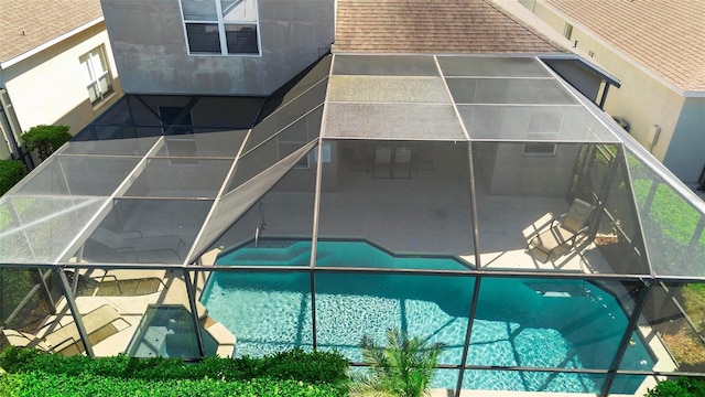 exterior space with an outdoor pool, glass enclosure, and a patio area