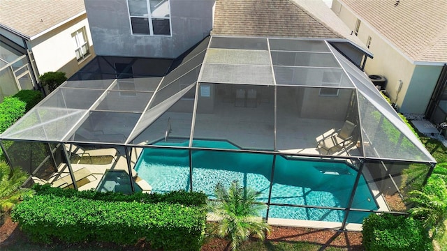 exterior space featuring glass enclosure, an outdoor pool, stucco siding, a shingled roof, and a patio area