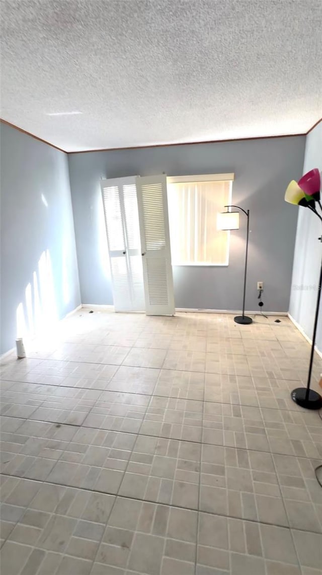 spare room featuring baseboards and a textured ceiling