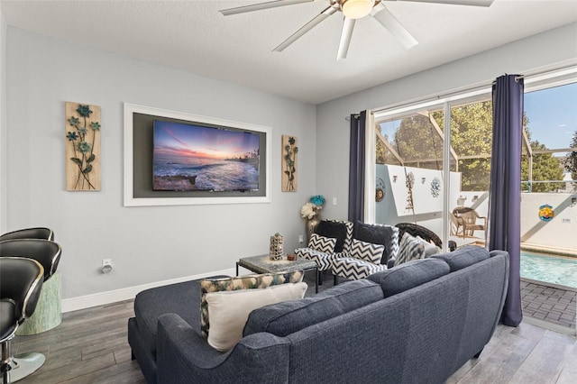 living room with a textured ceiling, baseboards, ceiling fan, and wood finished floors