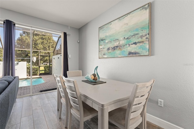 dining area with light wood-style flooring, a textured wall, and baseboards