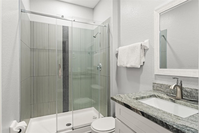 bathroom featuring vanity, toilet, and a stall shower