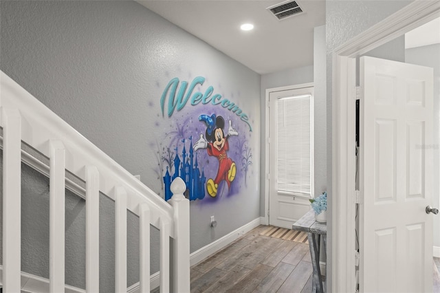 hallway with visible vents, baseboards, and wood finished floors