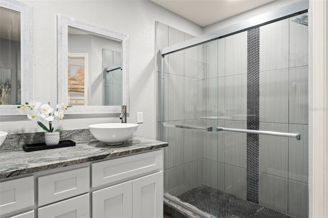 full bathroom featuring vanity, a shower stall, and a textured wall