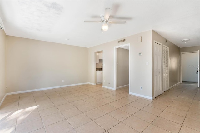 unfurnished room featuring light tile patterned flooring, visible vents, baseboards, and a ceiling fan