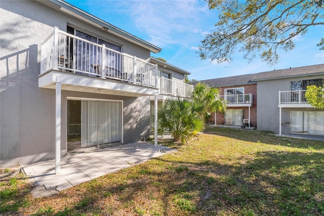 back of property with a patio, a yard, and stucco siding