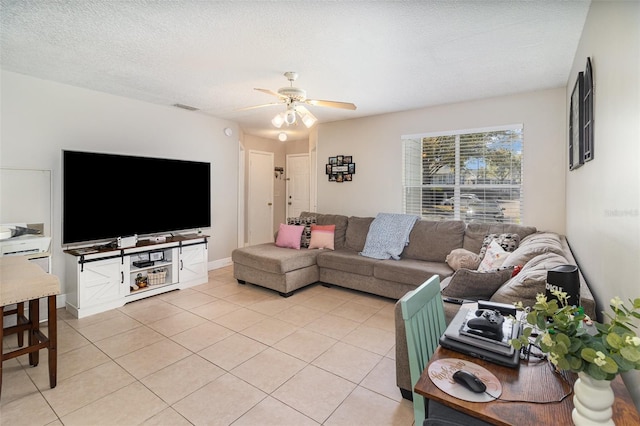 living area with light tile patterned floors, baseboards, visible vents, ceiling fan, and a textured ceiling