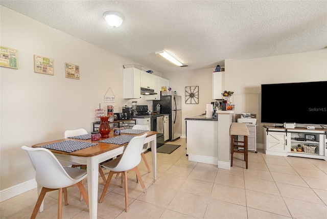 dining area with light tile patterned floors, a textured ceiling, and baseboards