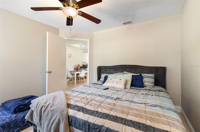 bedroom with visible vents, baseboards, a textured ceiling, and a ceiling fan