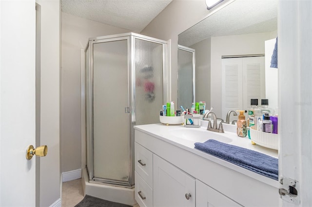 bathroom featuring baseboards, a stall shower, vanity, and a textured ceiling