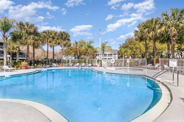 community pool with a patio area and fence