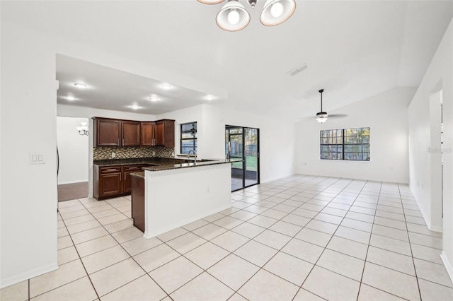 kitchen featuring light tile patterned floors, tasteful backsplash, dark countertops, and a healthy amount of sunlight