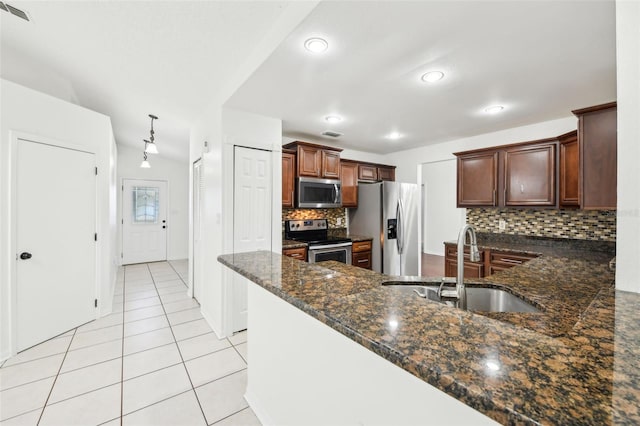 kitchen featuring light tile patterned floors, visible vents, a peninsula, a sink, and appliances with stainless steel finishes