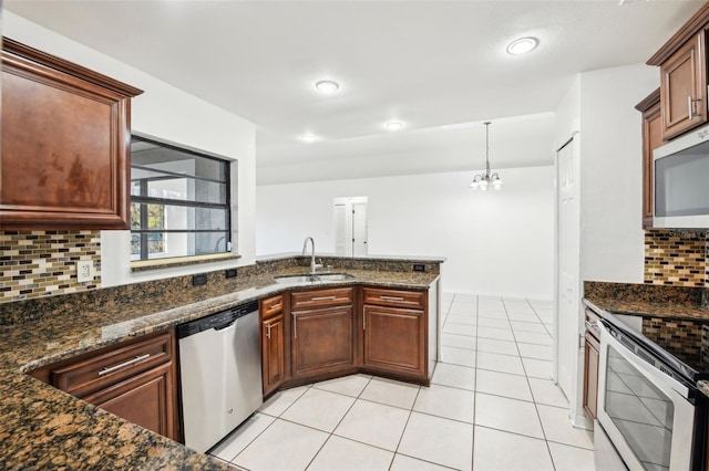 kitchen with light tile patterned floors, decorative backsplash, dark stone countertops, appliances with stainless steel finishes, and a sink