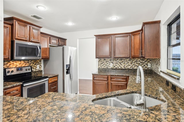 kitchen with a sink, visible vents, backsplash, and stainless steel appliances